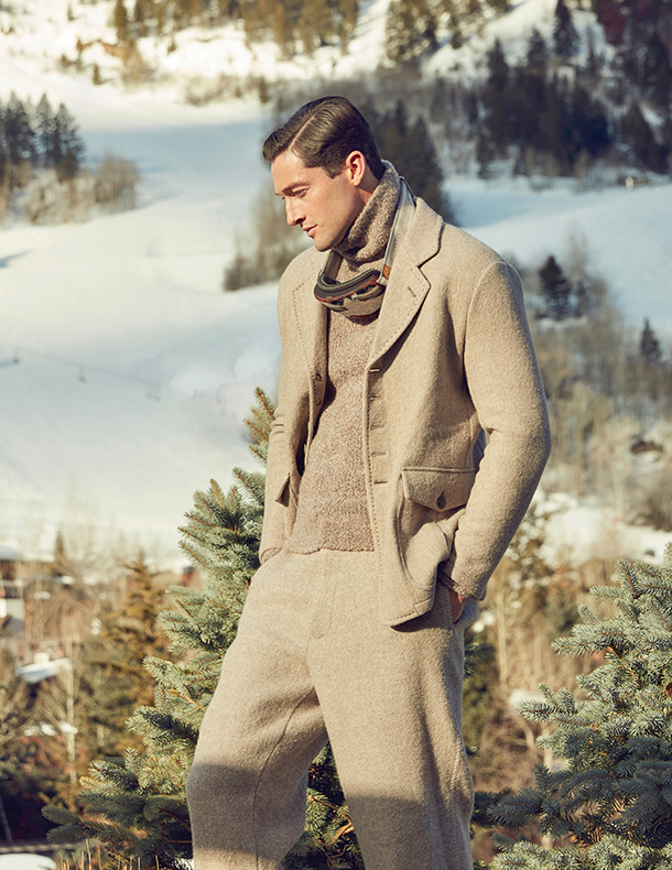 Man wearing monotone brown jacket, turtleneck sweater and trousers with ski goggles around his neck