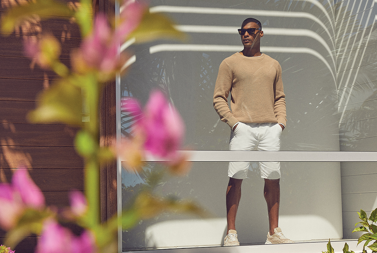 Man with sunglasses standing and looking out of large glass window