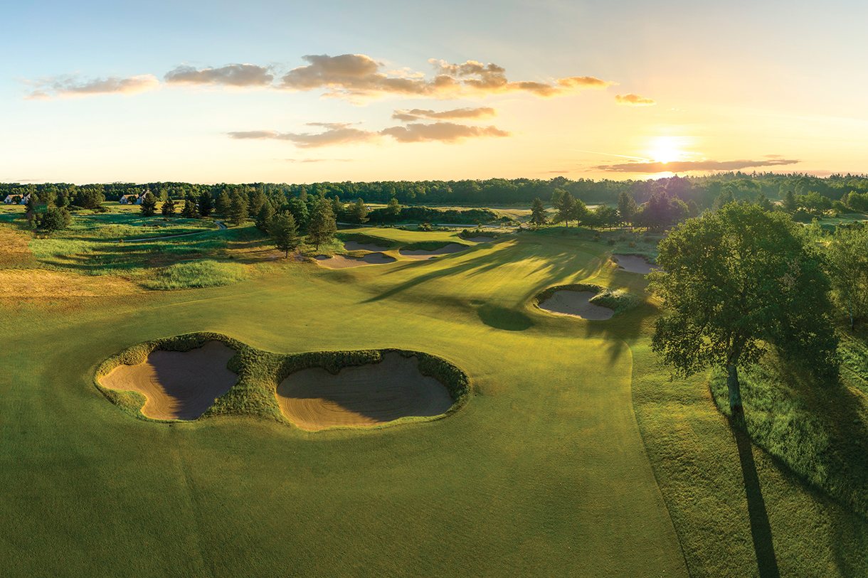 Sunset behind golf fairways with closeup of bunker.