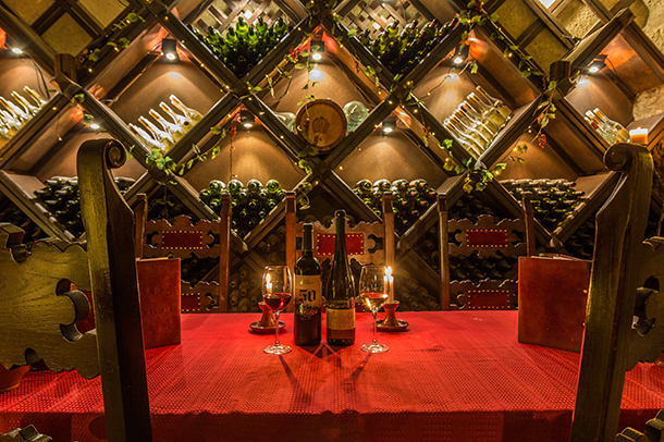 Interior of historical underground wine cellar with a red table and chairs used for wine tastings.