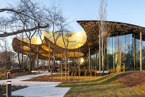 Nature inspired, unique modern building with glass walls and abstract shaped roof with cutout crater-like holes.