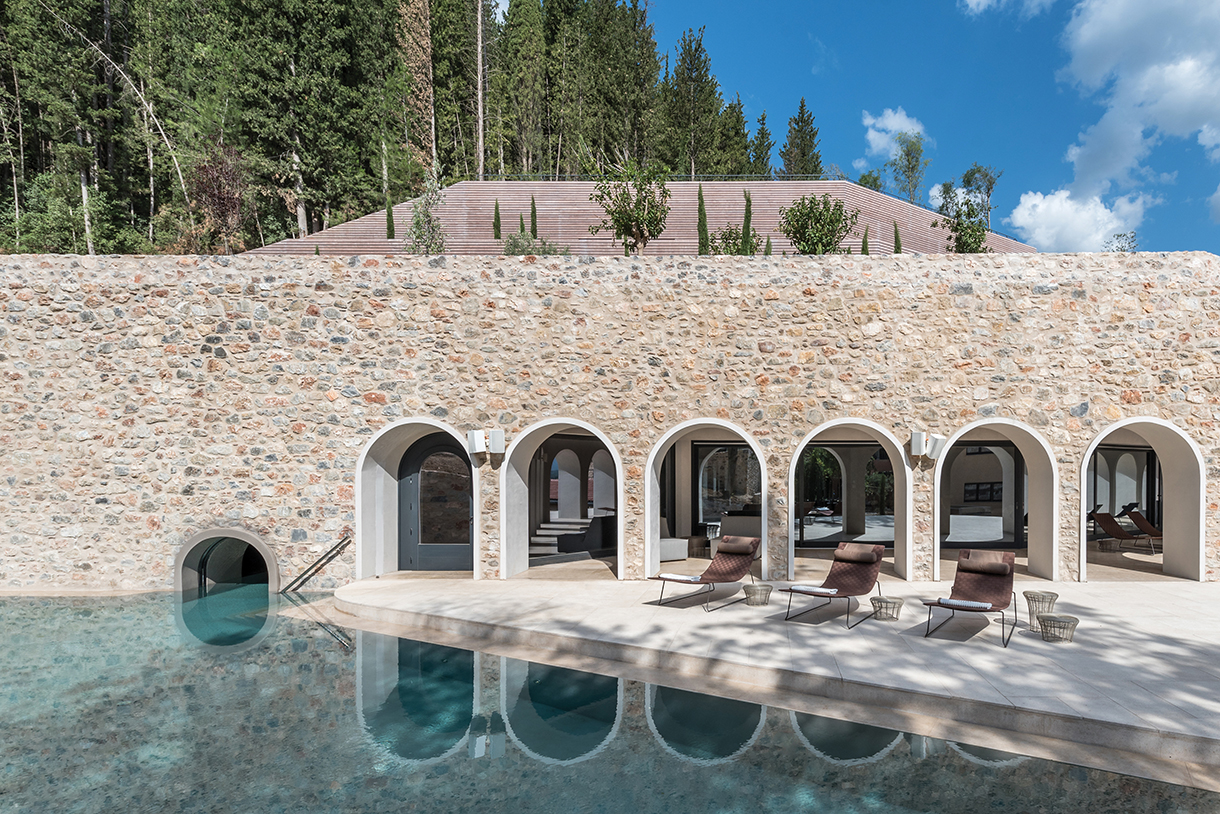 Beautiful outdoor infinity pool and lounge area with tall trees in the background