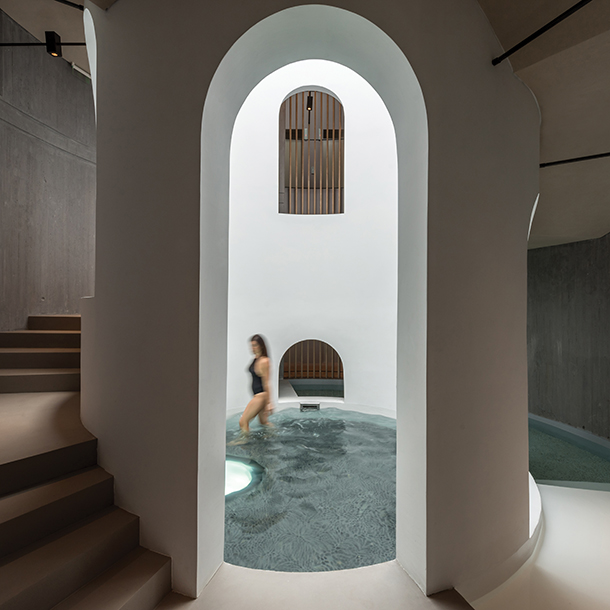 Woman wearing swimsuit standing inside tall water well for therapy footbaths