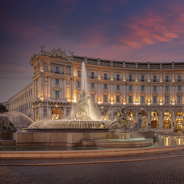 Hotel with classical Roman architecture and water fountain with bronze sculptures in front