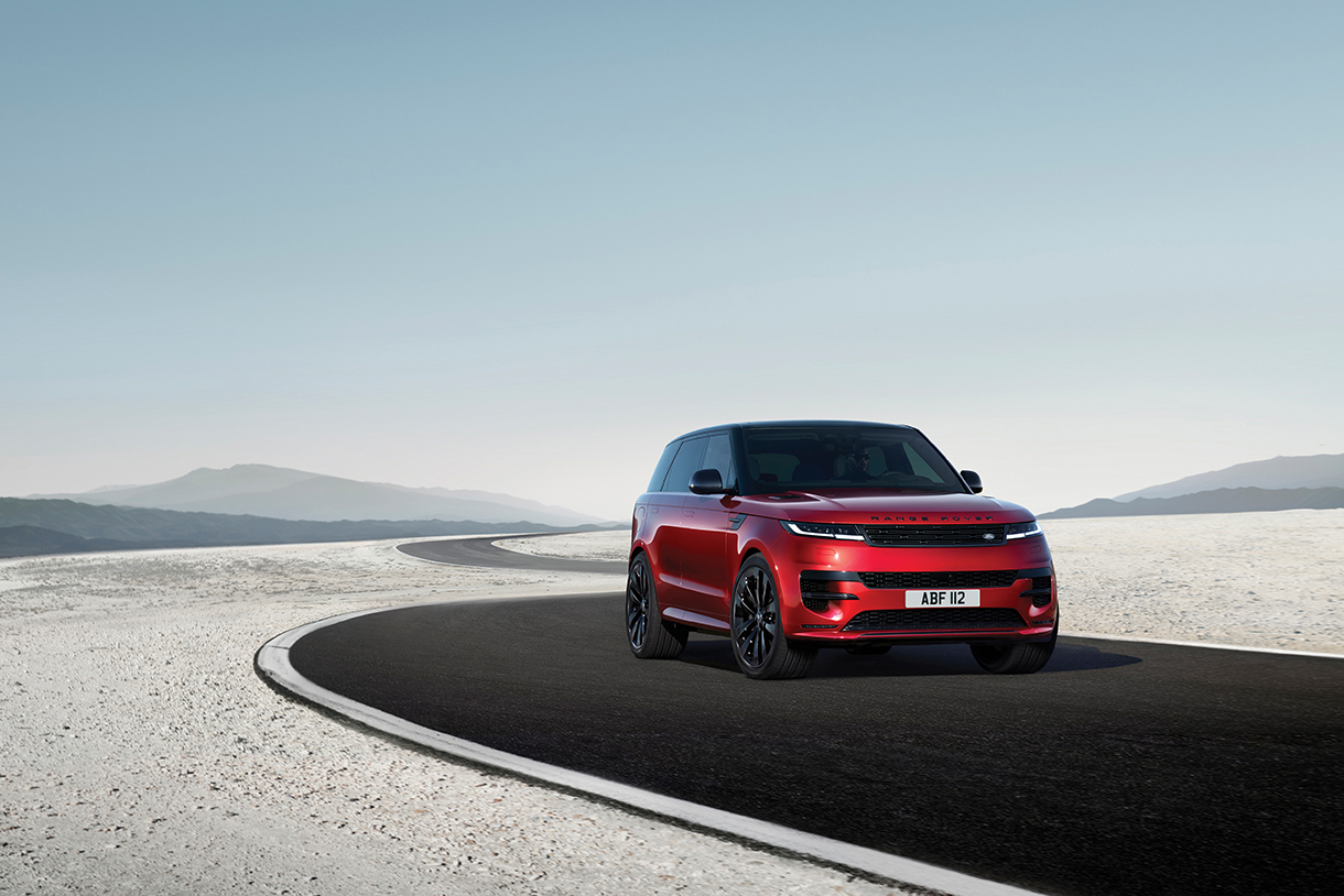 Front three-quarter view of red 2023 Range Rover Sport P440e Electric Hybrid parked on a paved road with mountains in the background