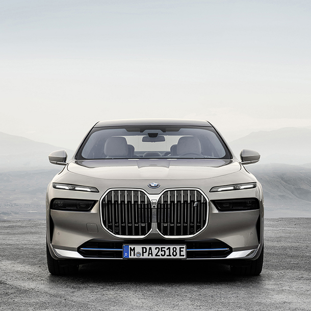 Closeup of the front view of silver BMW i7 xDrive60  with mountains in the background