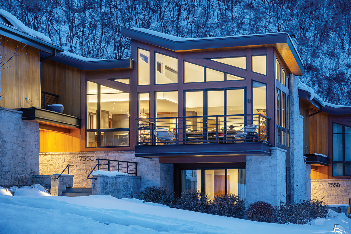 Exterior photo of vacation rental property in Aspen, Colorado. There is a balcony and wall made of glass windows and doors.